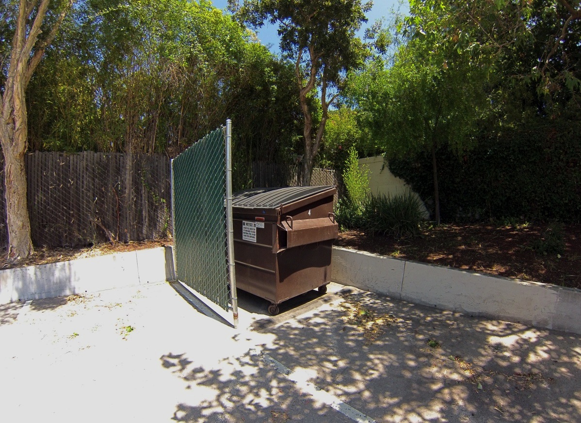 Dumpster hidden behind a fence
