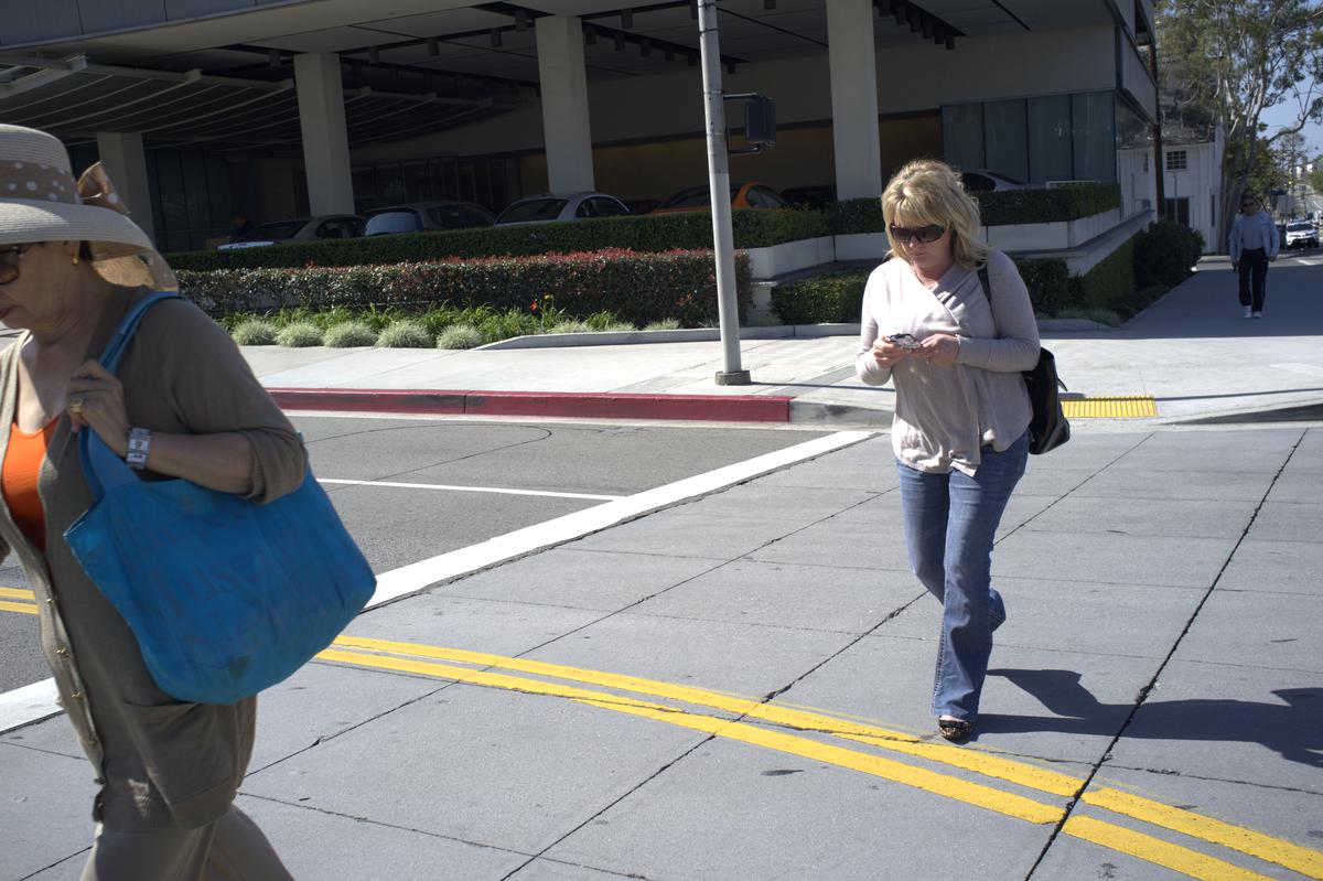 Woman crossing the street while typing on her phone